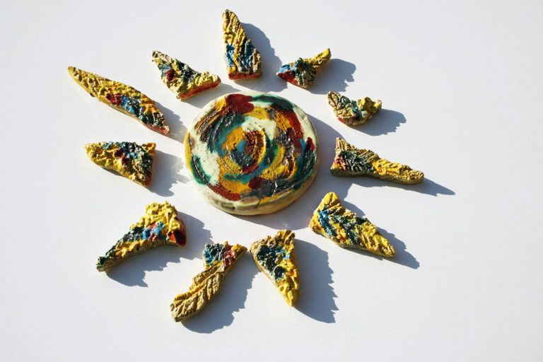 Scultura ceramica di piccolo formato in argilla bianca con raggi frammentati, graffi istintivi e smalti multicolore giallo, rosso e azzurro