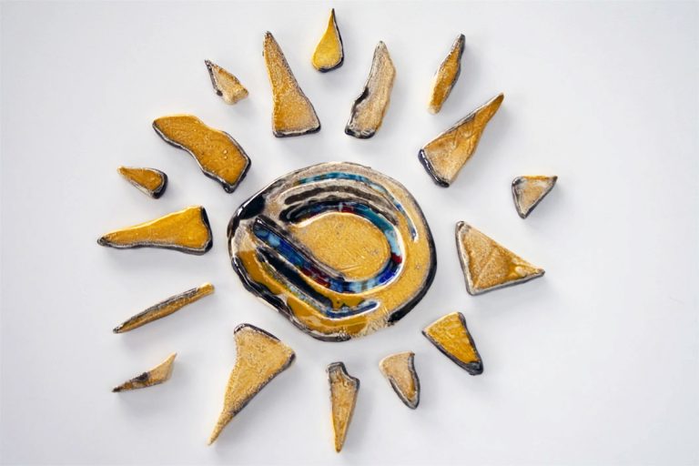 Piccolo sole in ceramica con finitura interamente gialla e un nucleo centrale impreziosito da strisce di vetro colorato fuso.