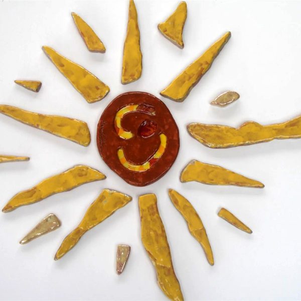 Sole in argilla rossa con raggi larghi e corposi in giallo intenso e solchi centrali con inserti di vetro fuso.