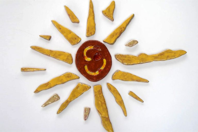 Sole in argilla rossa con raggi larghi e corposi in giallo intenso e solchi centrali con inserti di vetro fuso.