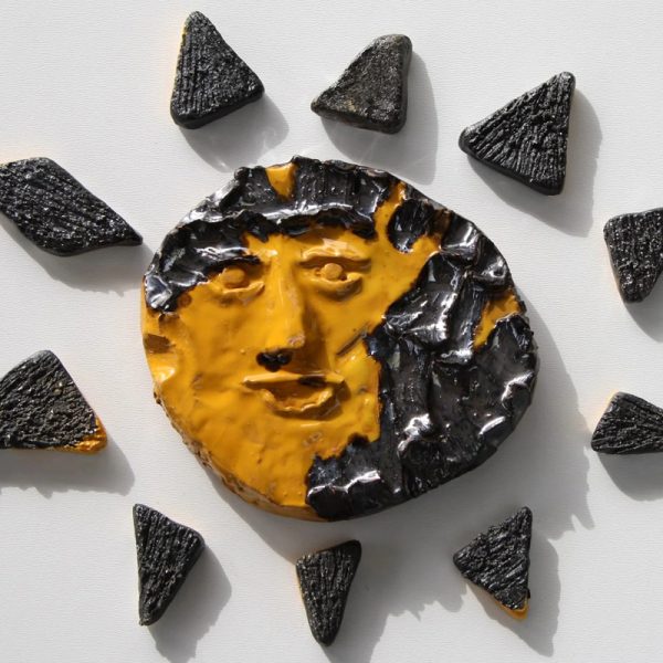 Sole in ceramica arancione con creste metalliche centrali e raggi alternati in giallo, arancio e nero ad effetto.