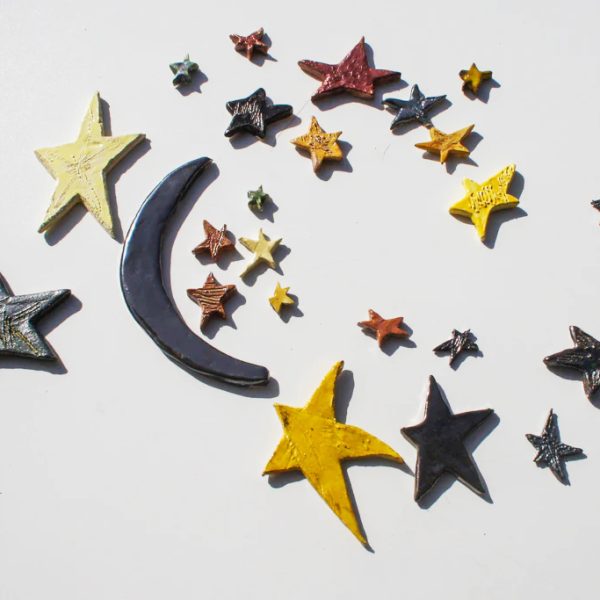 Piccola scultura di luna in ceramica bianca con smalto speciale cangiante e un seguito di stelle artigianali.
