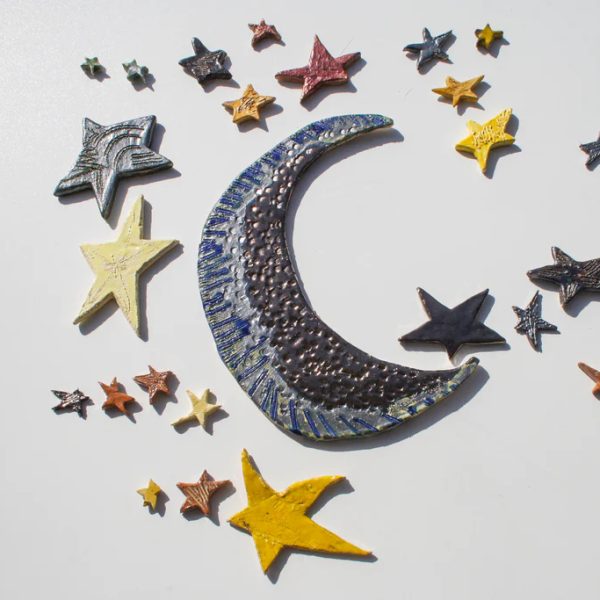 Grande installazione scultorea a forma di luna in argilla bianca con trame incise e finiture ceramiche splendenti.