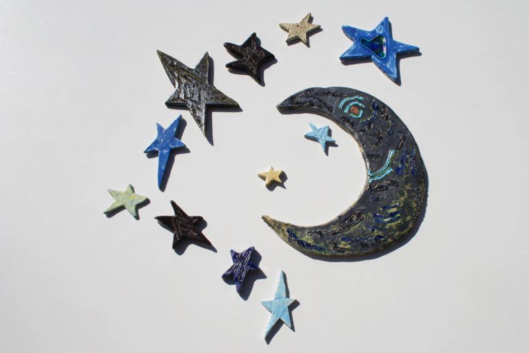 Grande luna in ceramica con maschera dal volto sorridente, smaltata in argento con accenti blu e azzurri.