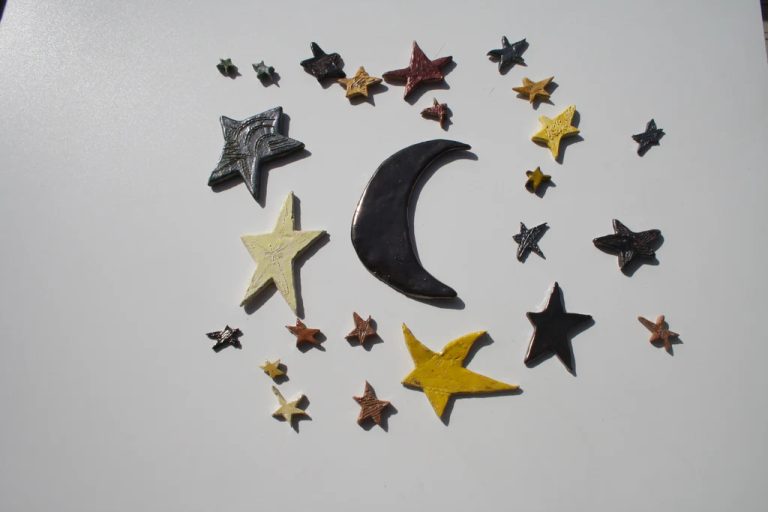 Luna in impasto semi-refrattario bianco con finitura smaltata morbida e sognante, affiancata da stelle coordinate.
