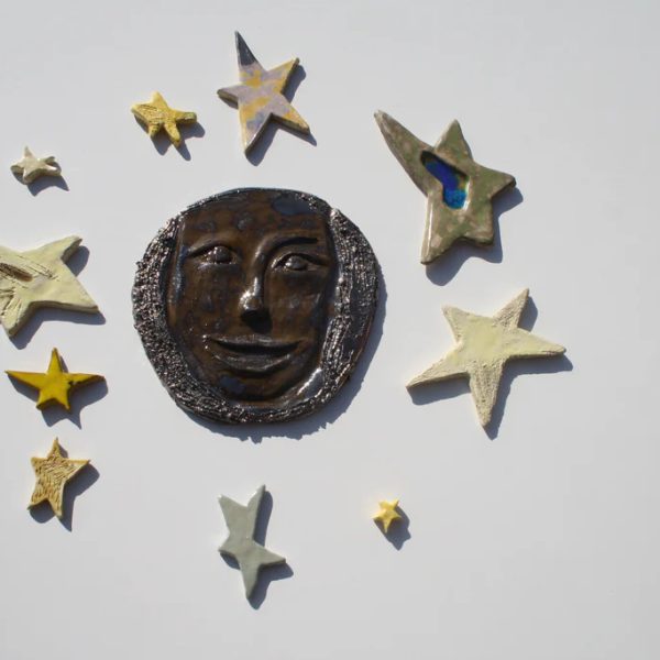 Luna piena in ceramica dal volto sorridente e solare, rifinita con due smalti ad effetto e stelle multicolore.