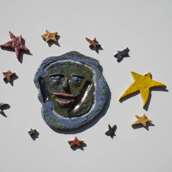 Luna piena in ceramica dal profilo espressivo e comunicativo, rifinita con smalti ad effetto e stelle assortite.
