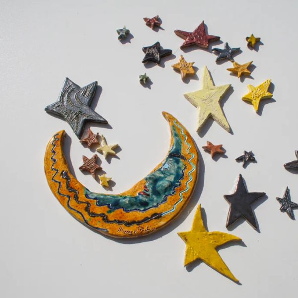 Luna crescente in ceramica bianca con punte allungate e volto interno smaltato in blu elegante, circondata da stelle.