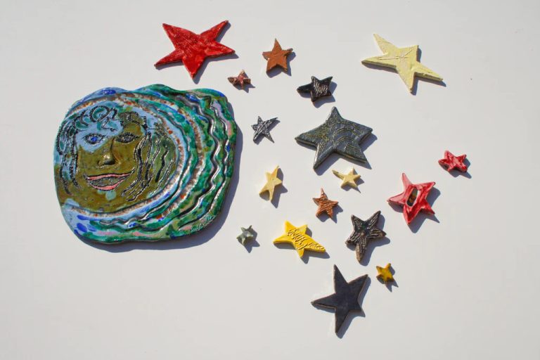 Grande installazione di luna in ceramica azzurra con intarsi in vetro fuso colorato ed espressione allegra, con stelle.