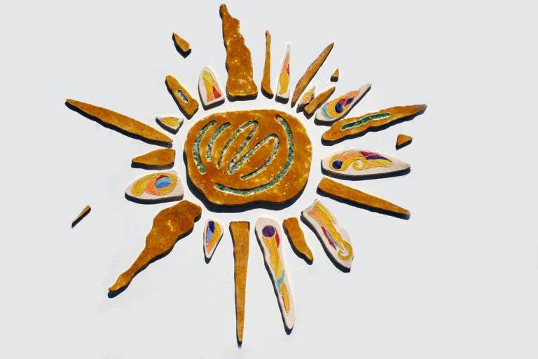 Grande sole artistico in argilla bianca con sfumature centrali color miele, tessere di vetro fuso e raggi cristallizzati multicolore.