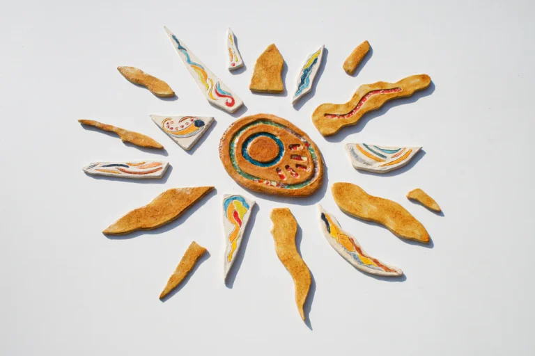 Grande sole scultoreo in argilla bianca con fulcro miele a inclusioni vitree e un'alternanza di raggi caldi, freddi e argento.