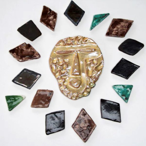 Piccolo sole scultoreo in ceramica dall'espressione extraterrestre rossa con raggi asimmetrici bianchi smaltati in marrone Dorré, nero e oro metallico.