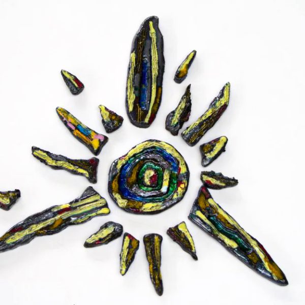 Piccolo sole in creta nera con graffiti manuali, sfumature gialle e arancioni e un nucleo centrale con inserti di vetro fuso.