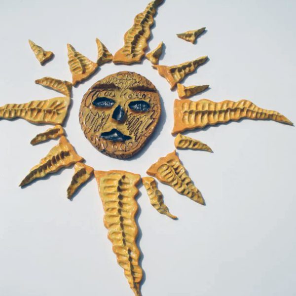 Grande sole a rosa dei venti con smalti gialli e arancioni e sfera centrale scolpita e graffita a mano.
