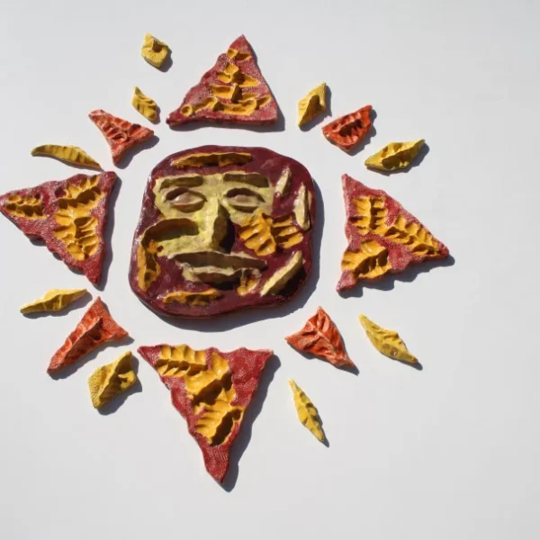 Sole medio-piccolo a rosa dei venti dominato dallo smalto rosso, con accenti gialli e una maschera centrale ironica.