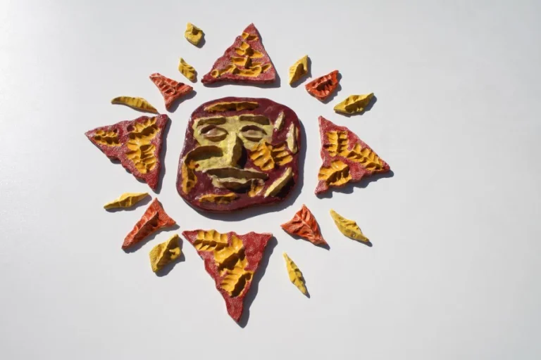 Sole medio-piccolo a rosa dei venti dominato dallo smalto rosso, con accenti gialli e una maschera centrale ironica.